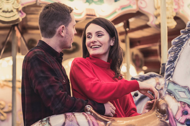 romantic couple taking a moment to kiss while riding horses on carousel - Fotografie, Obrázek