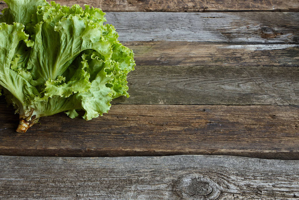 Tête de salade fraîche verte avec racine sur une vieille surface rugueuse en bois, concept de saine alimentation, accent sélectif
 - Photo, image