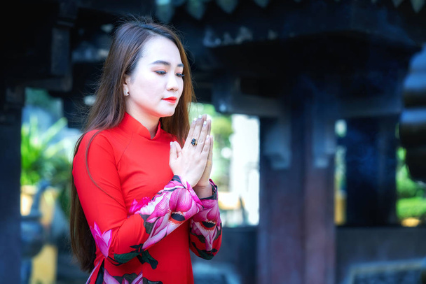 Ho Chi Minh City, Vietnam - 15 joulukuu 2019: vietnamilainen tyttö perinteisessä pitkämekossa tai Ao Dai teeskentely rukoilee rauhaa temppelin edessä kevätaamuna Ho Chi Minh Cityssä, Vietnamissa
 - Valokuva, kuva