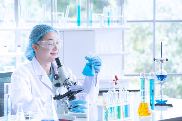 Ασιατικές γυναίκα επιστήμονας, ερευνητής, τεχνικός, ή φοιτητής διεξάγει έρευνα ή πειραματιστείτε με τη χρήση μικροσκόπιο που είναι Επιστημονικός εξοπλισμός στο ιατρικό, Χημείας ή Βιολογίας εργαστήριο - Φωτογραφία, εικόνα