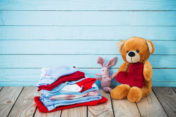 baby clothes and toy bear on old wooden background  - Fotoğraf, Görsel