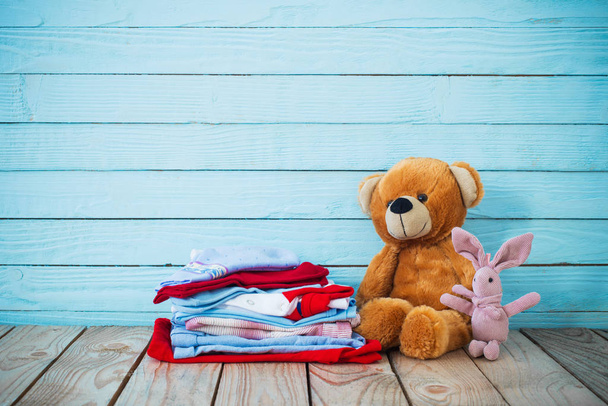 baby clothes and toy bear on old wooden background  - Foto, imagen