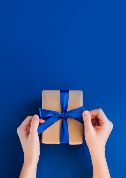 New Year's gift on a blue background, with a beautiful satin ribbon. Christmas. New Year's content. - Photo, Image