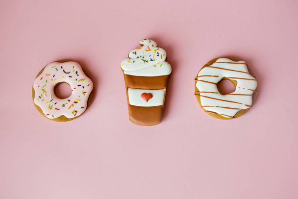 Fragrant gingerbread in the form of doughnuts on a pink background with sequins of small multi-colored stars and donut inscription. - Photo, Image