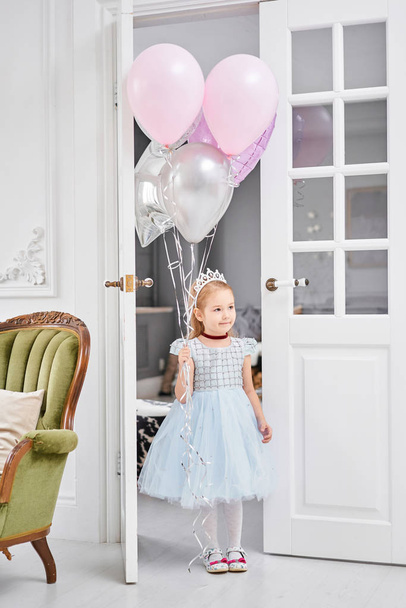 Birthday party. Happy cute little girl celebrating holiday with balloons. Adorable small child smiling with bunch of air balloons. - 写真・画像