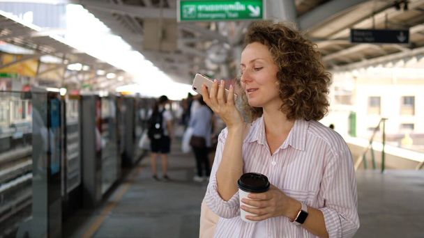 Trendy νεαρή γυναίκα μιλώντας μέσω φωνητικών μηνυμάτων στο κινητό τηλέφωνο μετακινούνται στην πόλη - Φωτογραφία, εικόνα