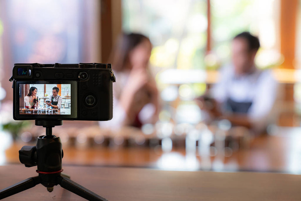 Genç Asyalı girişimci kafe kahve dükkanının video bloğu ve kafedeki kamerayla çevrimiçi pazarlama için sosyal medyada yaşıyor. Küçük işletme oluşturma ve tüketim kavramının başlangıcı için kullanılacak.  - Fotoğraf, Görsel
