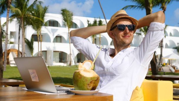 Joven hombre de negocios exitoso con ordenador portátil de relajación en la playa en Villa
 - Foto, imagen