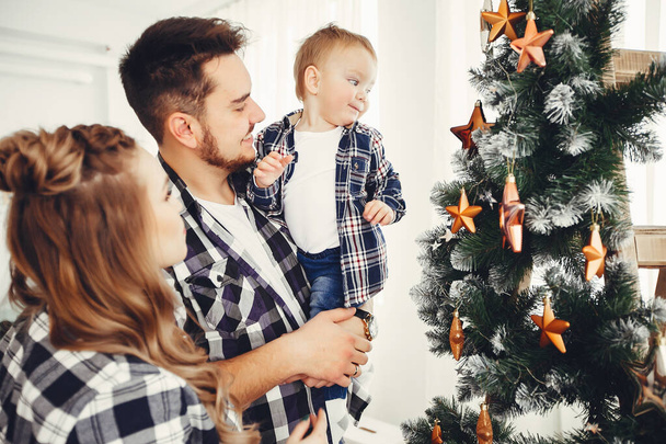 Cute family standing near Christmas tree - Foto, afbeelding