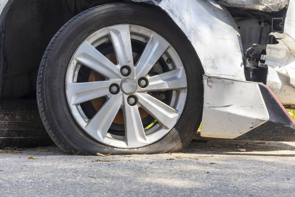 Ermüdeter, platter Reifen nach beschädigtem und versehentlich kaputtem weißen Auto vor weißem Hintergrund. Sparen mit Schneideweg.  - Foto, Bild