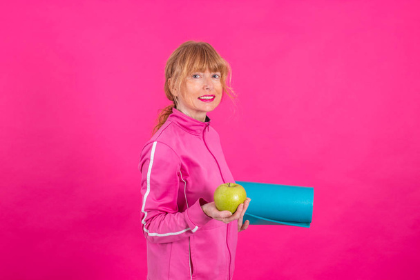 Elma ve spor paspası renkli bir kadın. - Fotoğraf, Görsel