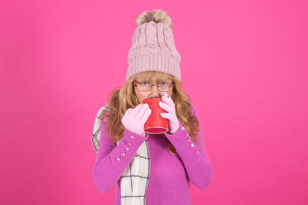 mujer adulta con taza de café o infusión caliente aislada sobre fondo de color
 - Foto, Imagen