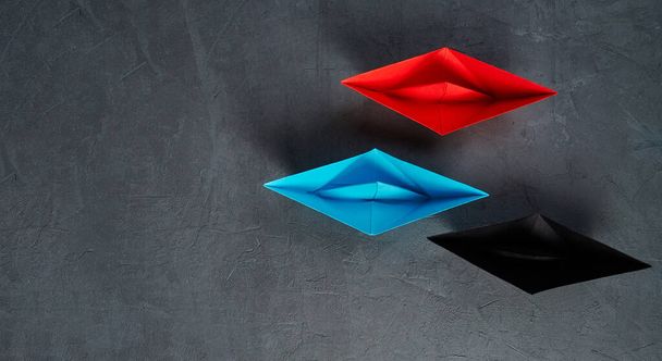 Business Concept, Paper Boat, the key opinion Leader, the concept of influence.Red.blue and black paper boat as the Leader on a gray concrete background, copy space, flat lay
. - Фото, изображение