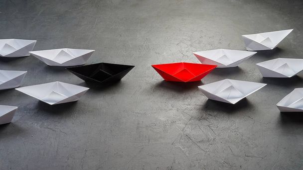 Ευκαιρίες Business Concept-Paper Boat βασική άποψη Leader, επιρροή έννοια. Ένα μαύρο χάρτινο σκάφος ως ηγέτης, που οδηγεί προς την κατεύθυνση των λευκών πλοίων πηγαίνει να συναντήσει το κόκκινο χάρτινο σκάφος που lea - Φωτογραφία, εικόνα