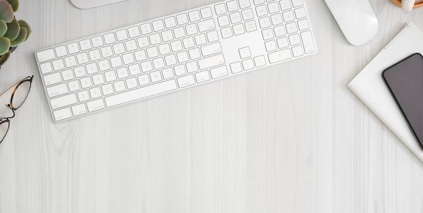 Обрезанный снимок удобного рабочего места со смартфоном, офисными принадлежностями и копировальным пространством на белом деревянном столе
  - Фото, изображение