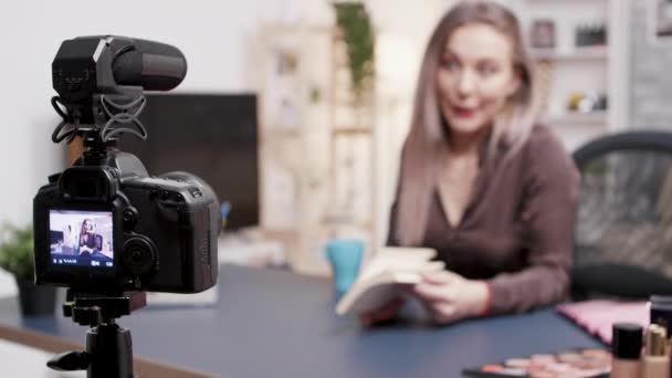 Vlogger haciendo una reseña de libro en fron de la cámara en su estudio creativo
 - Imágenes, Vídeo
