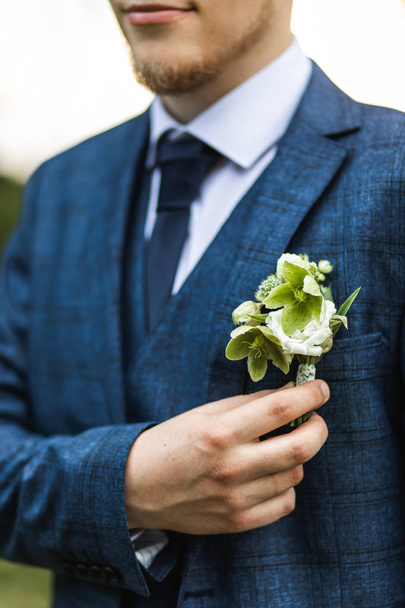 Stylish groom in classic blue suit holding green flower boutonni - Zdjęcie, obraz