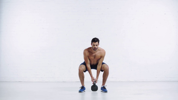 sportovec dělá sedy up s hmotností na bílém pozadí - Záběry, video
