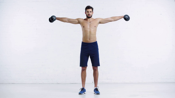sportsman exercising with dumbbells on white background - Footage, Video