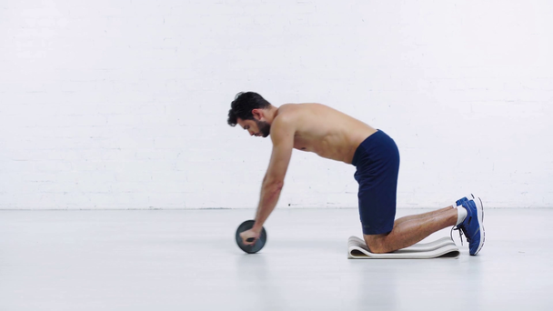 sportman die traint met een fitnesswiel op een witte achtergrond - Video