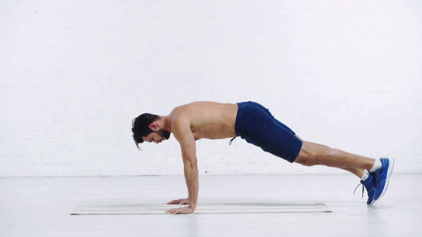 sportsman exercising in one legged plank pose on white background - Video, Çekim