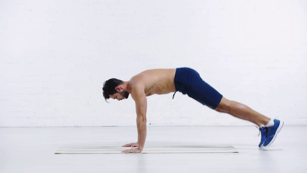 sportman oefenen in plank pose op witte achtergrond - Video