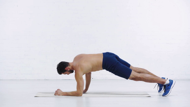 sportsman doing low plank on white background - Záběry, video