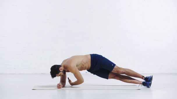 sportsman doing side plank on white background - Footage, Video