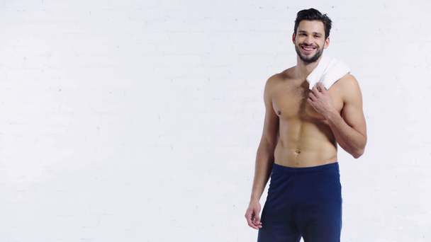 sportsman with towel smiling at camera on white background - Filmagem, Vídeo