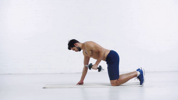 sportsman exercising with dumbbell on white background - Video, Çekim