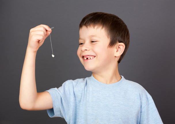αγόρι δείχνουν χαμένο δόντι σε ένα νήμα - Φωτογραφία, εικόνα