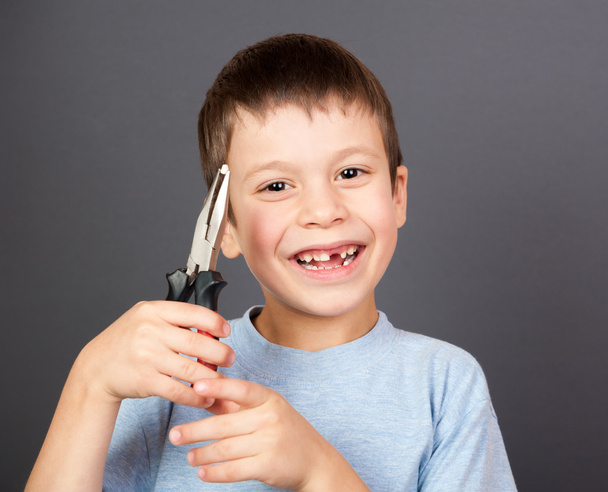 boy holds a lost tooth in the pliers - Photo, Image