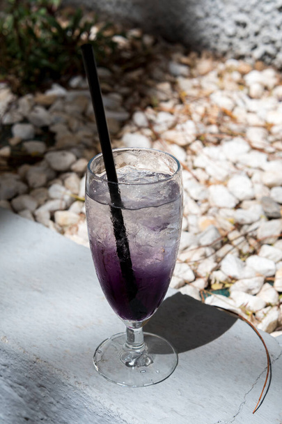 Photo of a glass with a straw and a purple drink - Photo, Image