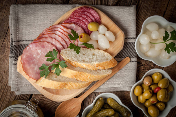 Tapas with sliced sausage, salami, olives, marinated onions, cuc - Fotó, kép