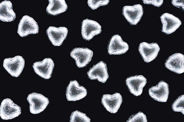Вид сверху сладостей в фольге в форме сердца, изолированных на черном
 - Фото, изображение