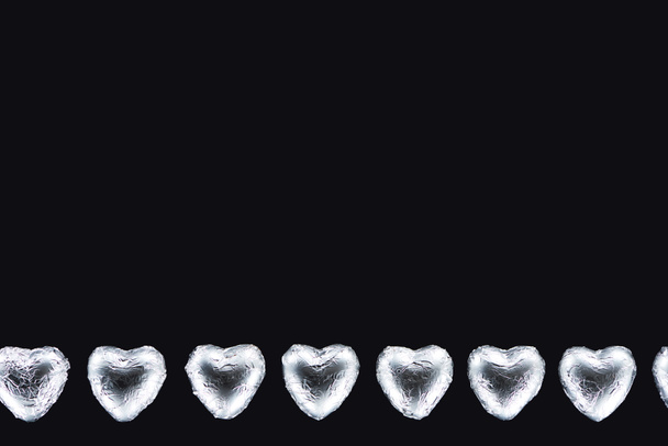 Bovenaanzicht van hartvormige snoepjes geïsoleerd op zwart met kopieerruimte - Foto, afbeelding