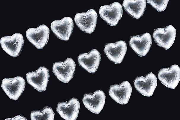 Vue de dessus des lignes de bonbons en forme de coeur dans une feuille isolée sur noir
 - Photo, image