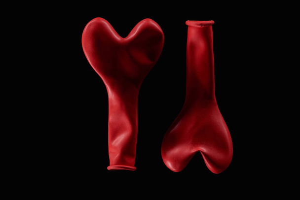 Top view of two red balloons in heart shape isolated on black  - Foto, Imagen