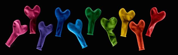 Top view of colorful rubber balloons in heart shape isolated on black, panoramic shot - Fotografie, Obrázek