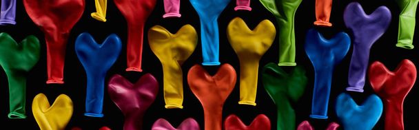 Top view of colorful heart shaped balloons isolated on black, panoramic shot  - Foto, afbeelding