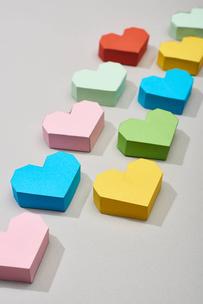 Čáry s barevnými papíry ve tvaru srdce na šedém pozadí - Fotografie, Obrázek