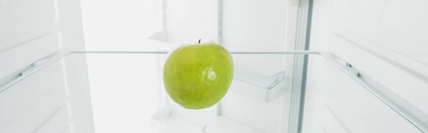 Verse groene appel in koelkast met open deur geïsoleerd op wit - Foto, afbeelding