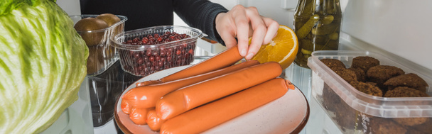 Cropped view of woman taking sausage from fridge with food on white background, panoramic shot - Photo, Image