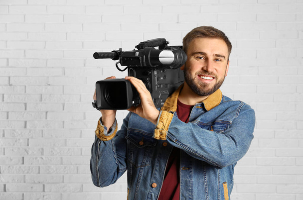 Operator with professional video camera near white brick wall - Foto, Imagem