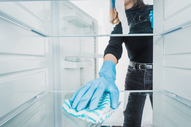 Gewassen weergave van meisje schoonmaken koelkast met vod geïsoleerd op wit - Foto, afbeelding