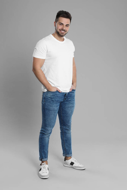 Young man in stylish jeans on grey background - Fotoğraf, Görsel