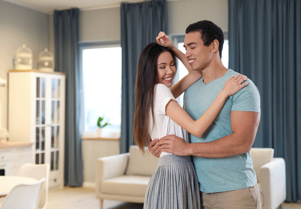 Lovely young interracial couple dancing at home - 写真・画像