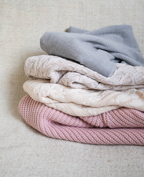 Stack of warm knitted woolen sweaters pastel shades - Foto, imagen