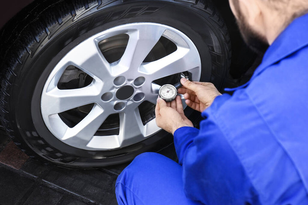 Mechanic checking tire air pressure at car service, closeup - Photo, image