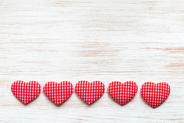 Valentine's Day concept. Valentines day background with line of red textile hearts on wooden planks. - 写真・画像